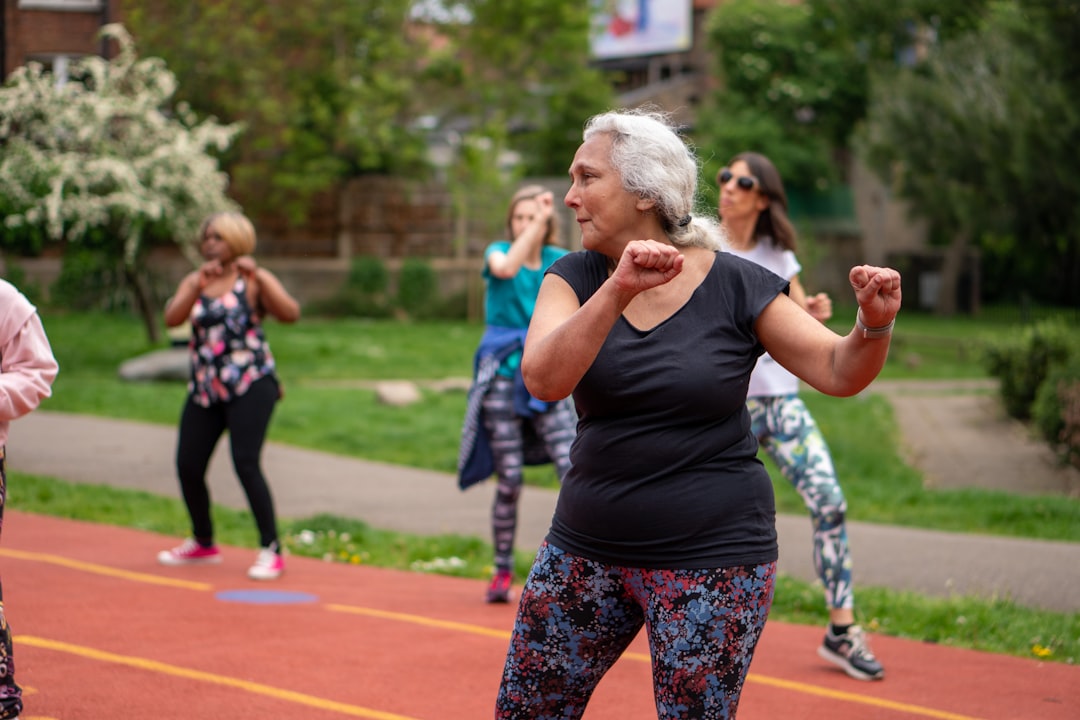 An older woman does exercises at an outdoor fitness class.