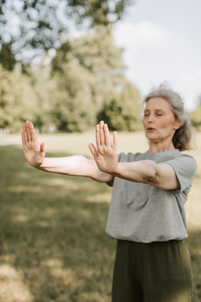 Senior woman practicing Tai Chi in a sunny park, focusing on mindfulness and healthy lifestyle.